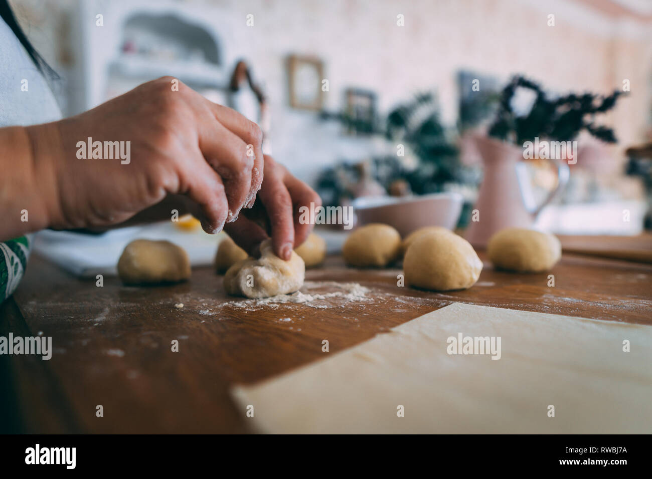 Le mani di una donna in cucina formatura di impasti palle. La formazione di palline di pasta per la cottura sul tavolo di legno. Foto Stock
