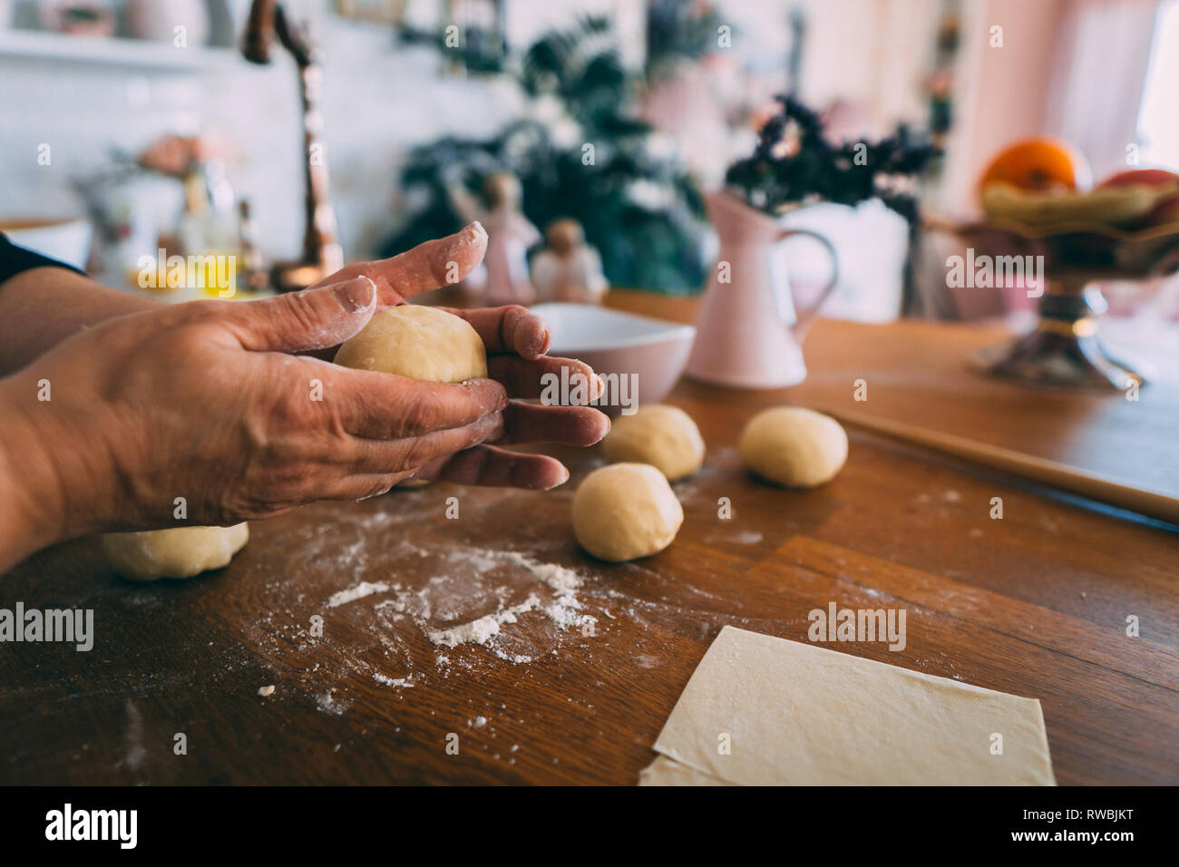Le mani di una donna in cucina formatura di impasti palle. La formazione di palline di pasta per la cottura sul tavolo di legno. Foto Stock