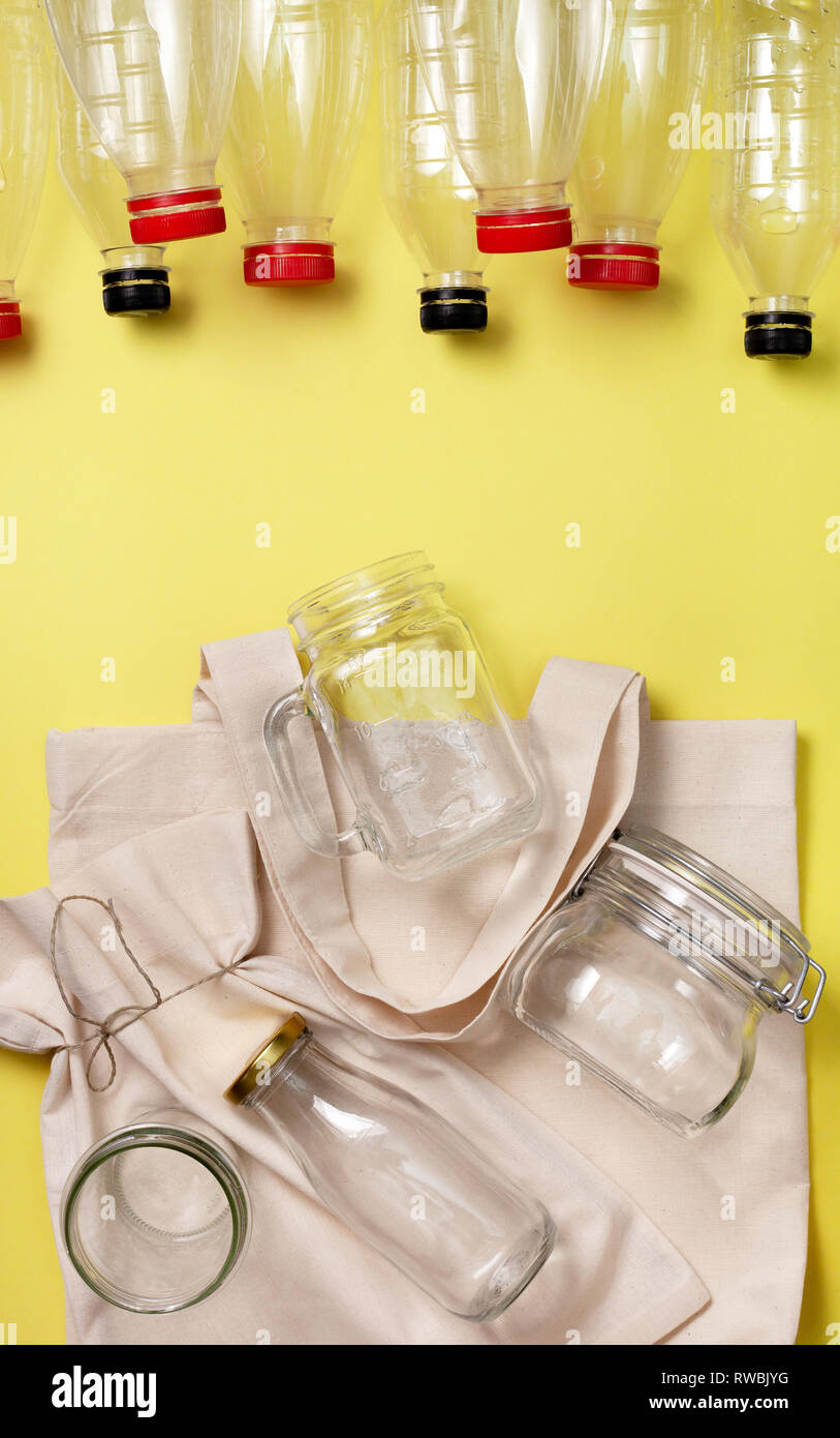 Libera in plastica, eco vivere. eco bag, vasetti di vetro e le bottiglie di plastica su uno sfondo giallo. vista da sopra Foto Stock