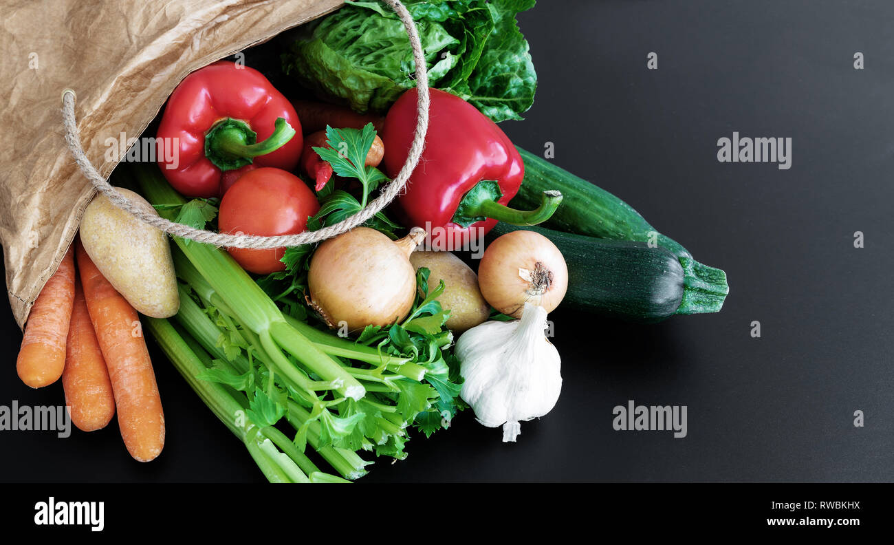 Fresche verdure organiche ha acquistato sul mercato settimanale in carta marrone sacchetto contro scuro dello sfondo della tabella Foto Stock