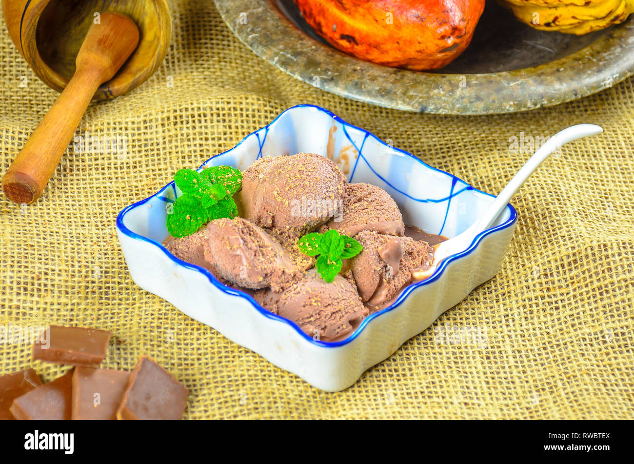 In casa fatto tutto artigianelmente gelato al cioccolato in una ciotola in ceramica con cucchiaino e cacao Cialde sullo sfondo. Foto Stock