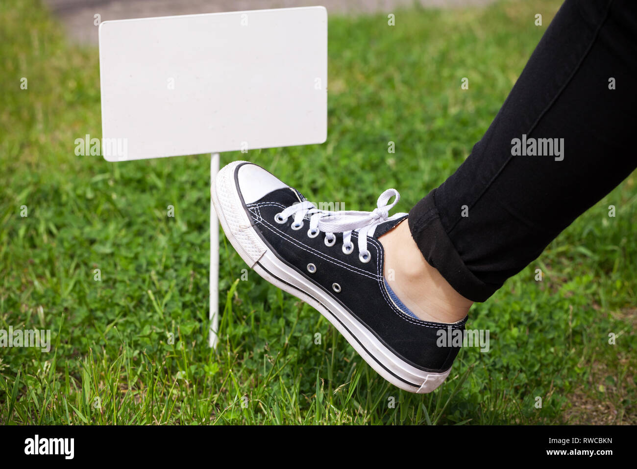Gli adolescenti piede calci piccolo banner bianco in piedi su un prato verde Foto Stock