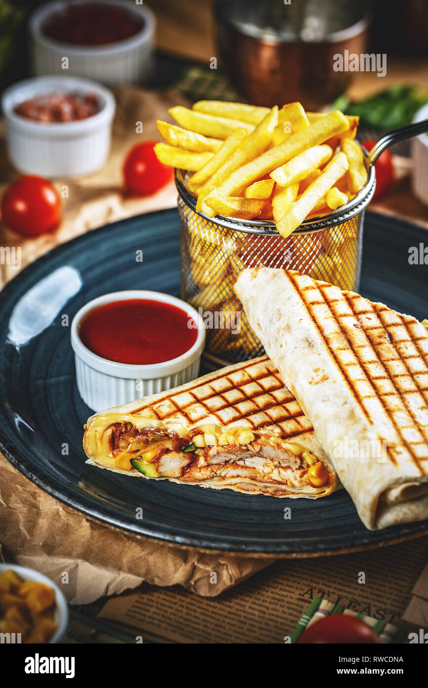 Pub snack. Tortilla avvolge con petto di pollo alla brace servite con patatine e salsa di peperoncino Foto Stock