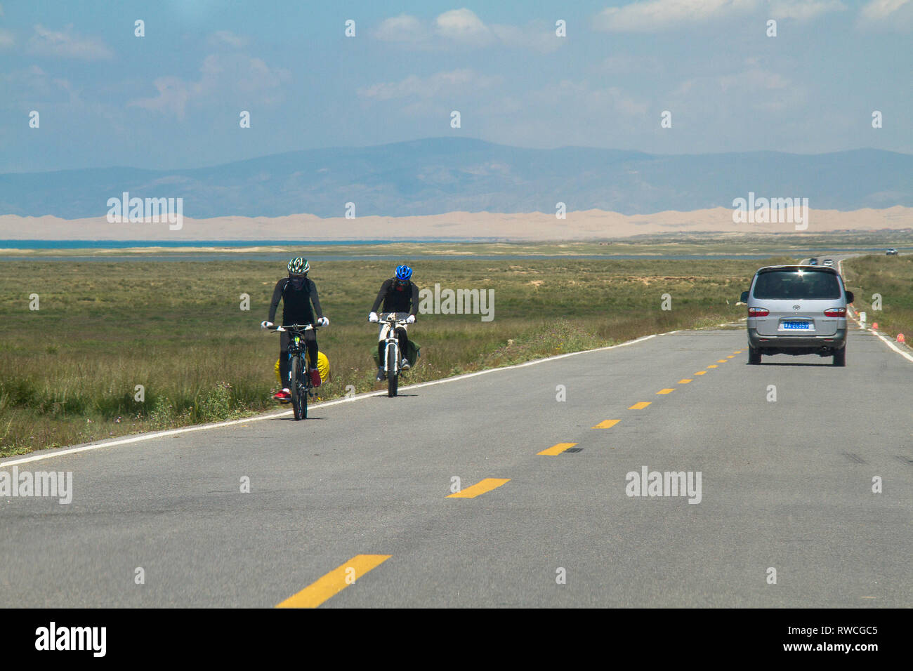 Una coppia di ciclisti cinesi un viaggio su una autostrada vicino Lago di Qinghai in Cina durante una gita in bicicletta road trip. Foto Stock