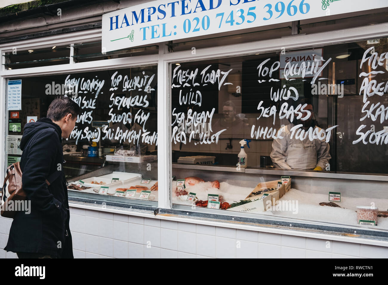 London, Regno Unito - 2 Marzo 2019: persone dal pescivendolo stallo a Hampstead centro comunitario nel mercato Hampstead, un affluente area residenziale di Londra favou Foto Stock
