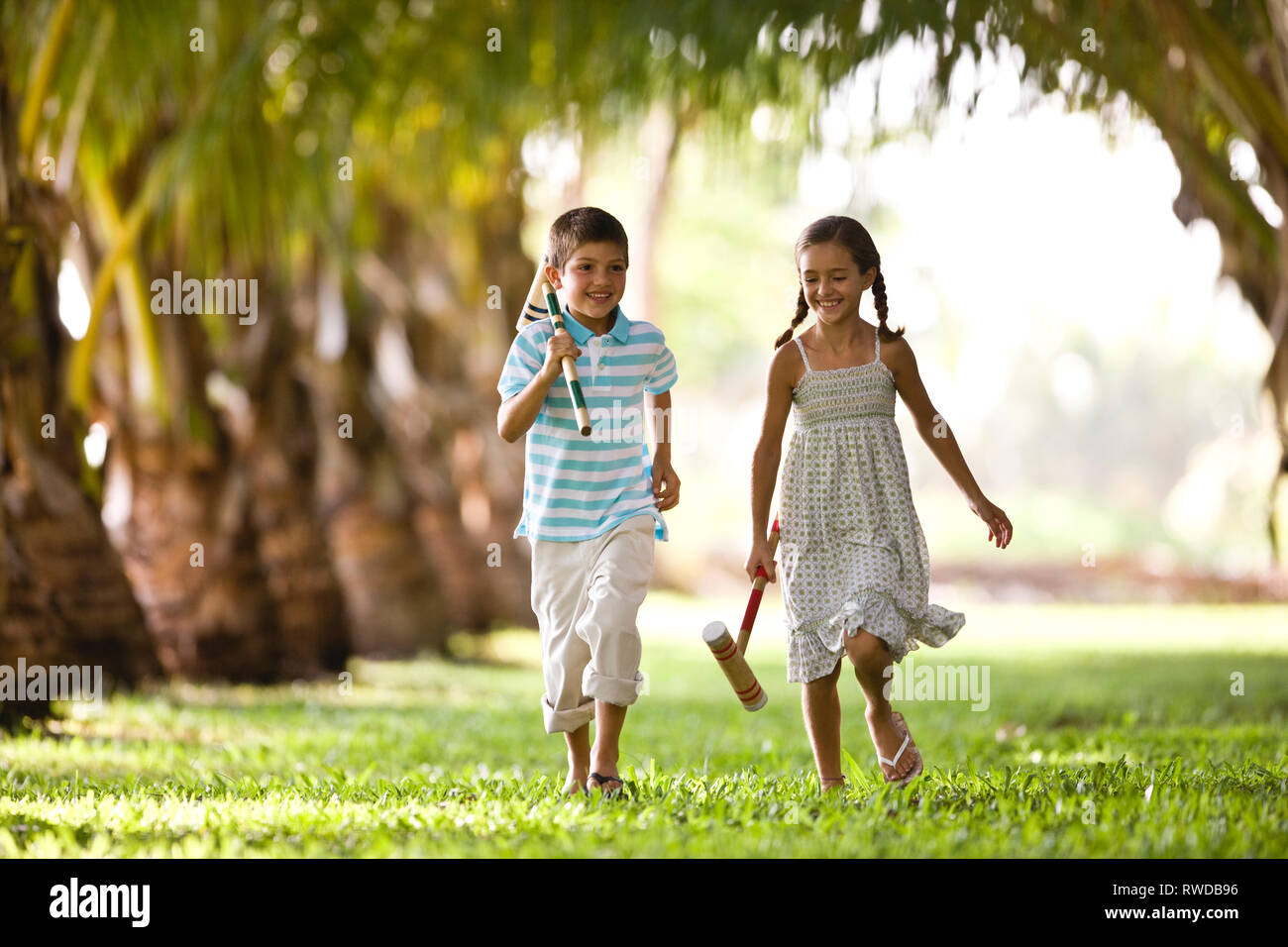 Fratello e Sorella in esecuzione insieme holding croquet mallets. Foto Stock