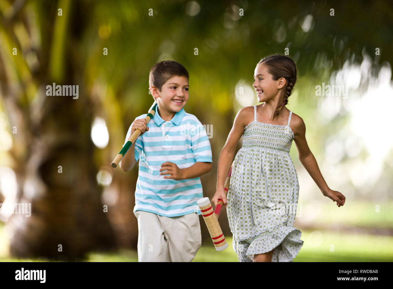 Fratello e Sorella in esecuzione insieme holding croquet mallets. Foto Stock