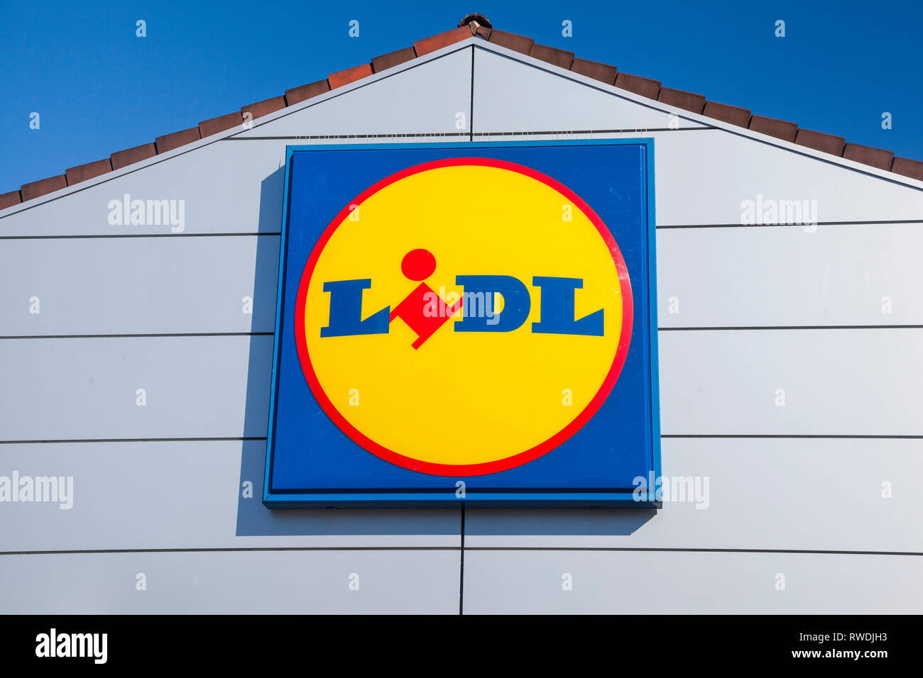 Il segno di Lidl e il logo contro un luminoso cielo blu sulla parte anteriore del negozio Lidl a Farnham, Surrey. Foto Stock