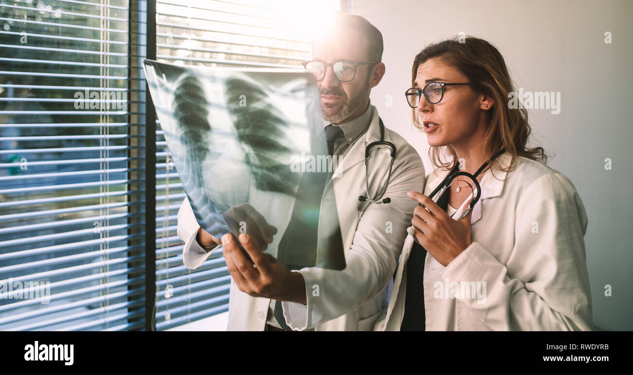 I colleghi medici guardare la x-ray del paziente e discutere nel corso del trattamento. Maschio e femmina medici guardando film a raggi x e la diagnosi di pa Foto Stock