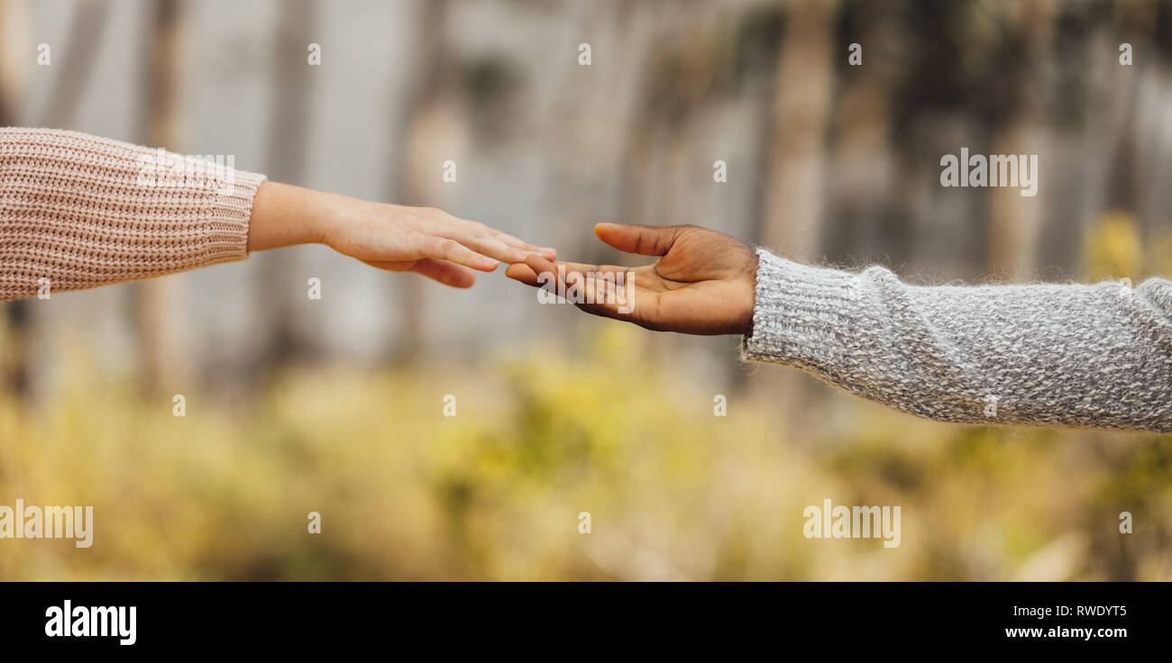 Multi-etnico giovane mani di raggiungere e toccare all'esterno. Giovane si avvicinano gli uni agli altri. Maschi e femmine di mani toccano con le dita. Foto Stock