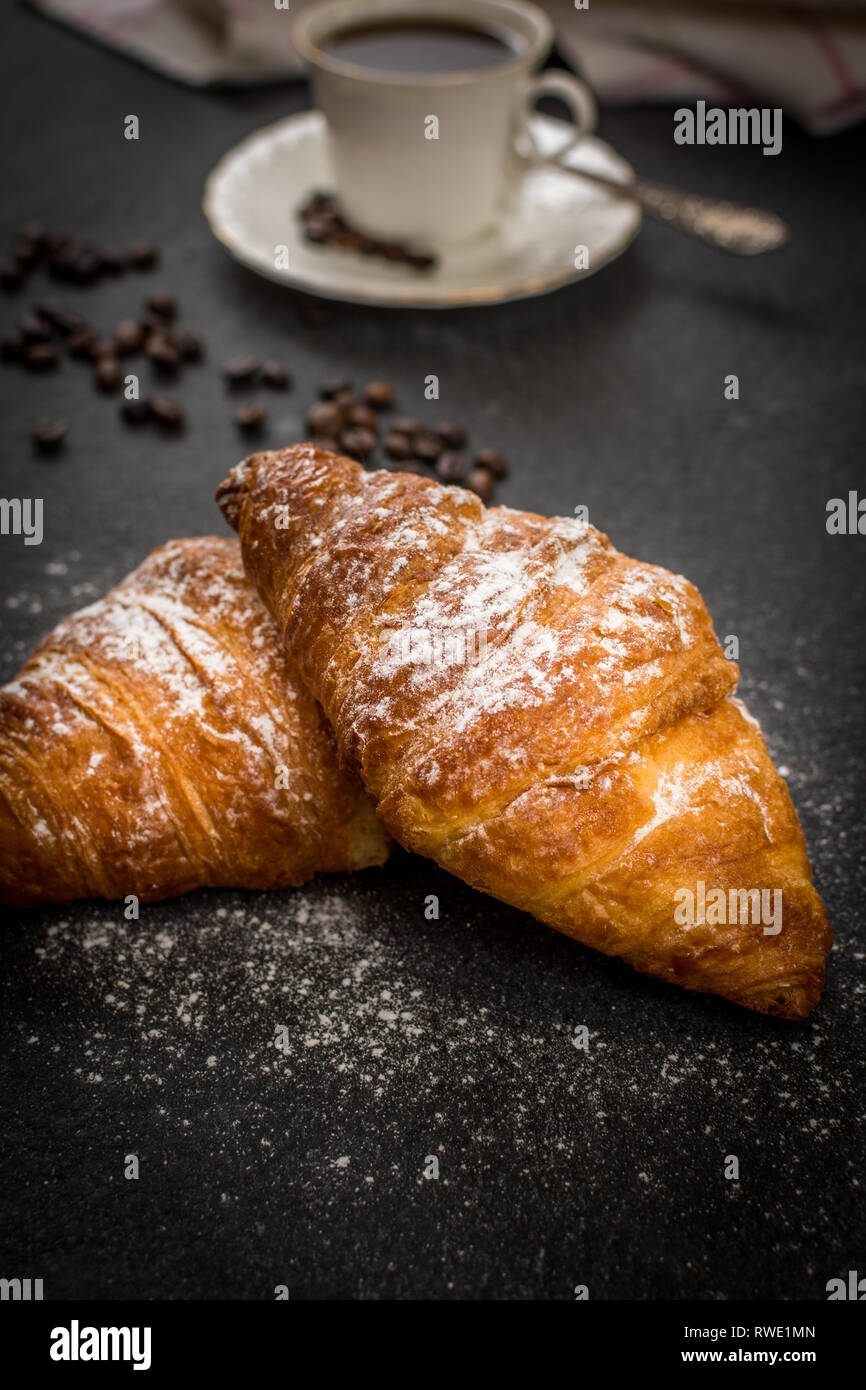 Tradizionale prima colazione francese croissant con zucchero e caffè nero sul tavolo di pietra Foto Stock
