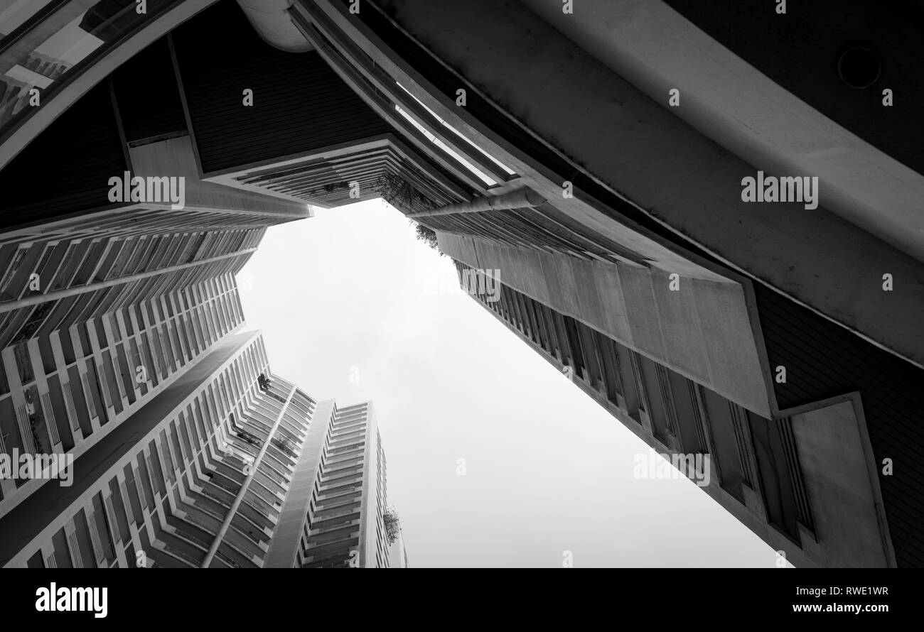 Vista dal basso del grattacielo edificio contro il cielo grigio e le nuvole. Ricerca di vista in edificio di appartamenti in città. Real estate e costrutto aziendale Foto Stock