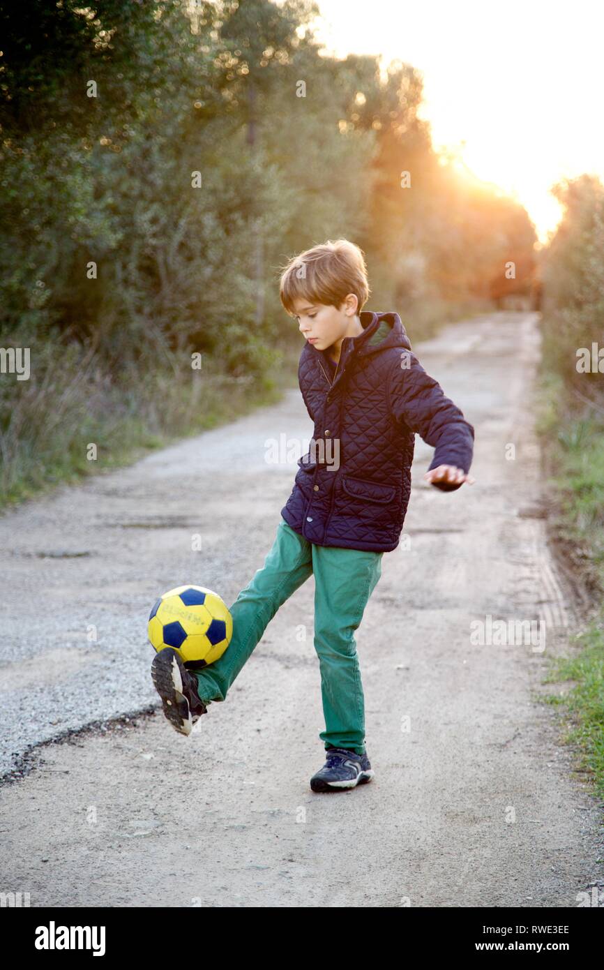 Ragazzo giovane divertirsi a giocare a calcio al tramonto Foto Stock