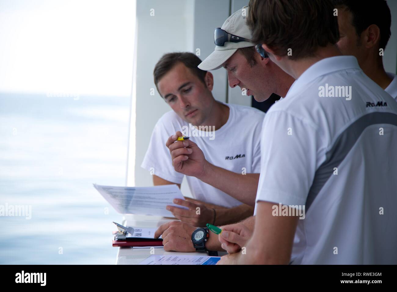 Close up di 3 equipaggi Superyacht sul ponte con lo sfondo del mare di navigazione di pianificazione Foto Stock