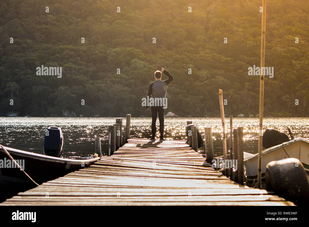 Uno stile di vita tranquillo colpo di giovane uomo a bordo di un dock - tramonto a Florianópolis - Santa Catarina - Brasile Foto Stock