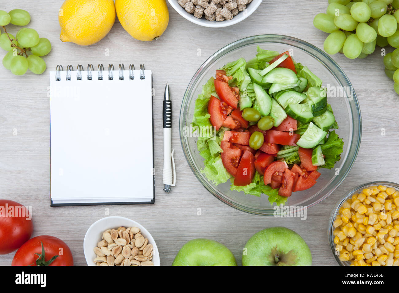 Notebook con un programma di dieta con frutta e verdura fresche e un lato piatto sul tavolo vista superiore Foto Stock