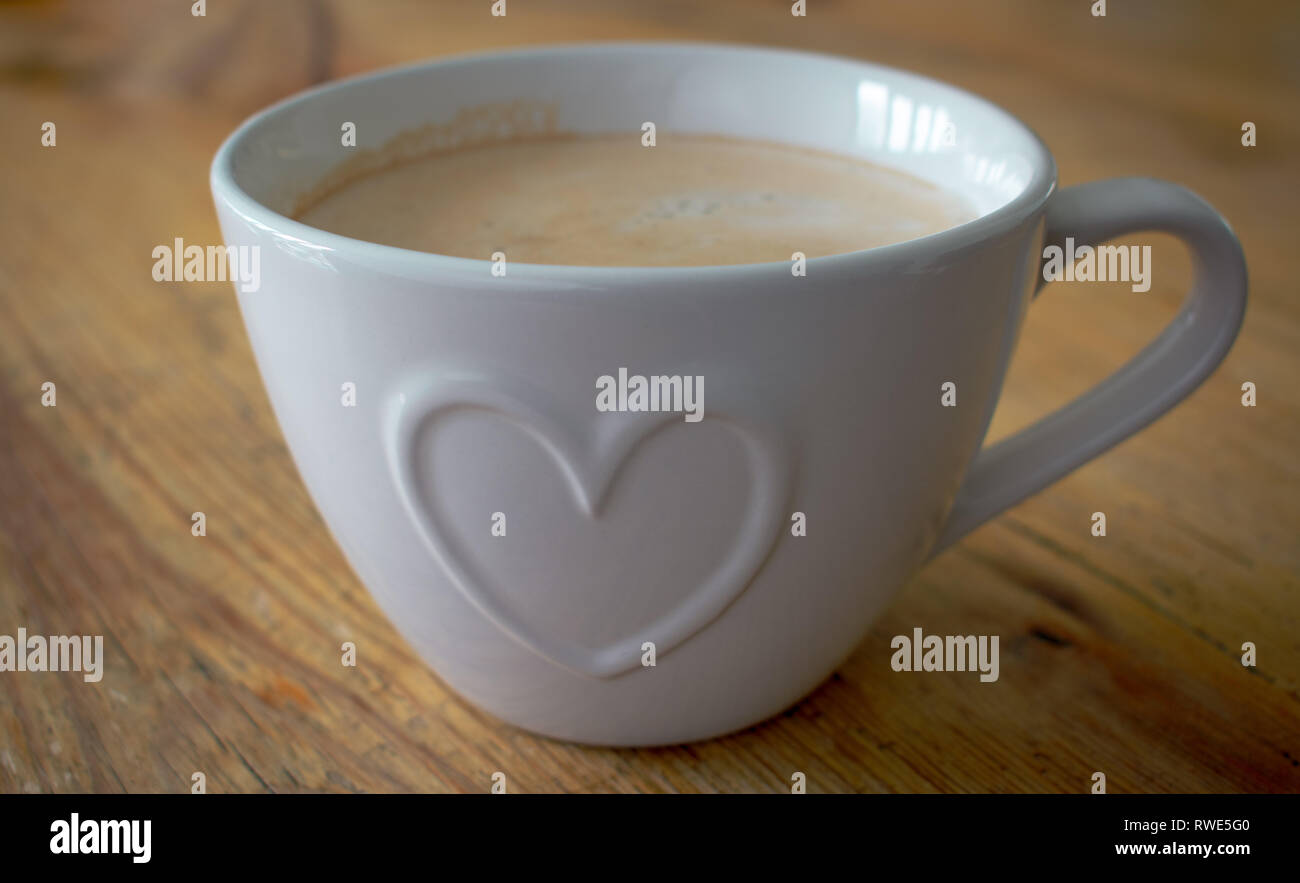 Tazza da caffè con forma di cuore, focus è il cuore al centro della tazza con profondità di campo per le altre aree, dando un leggero effetto sfocato. Foto Stock