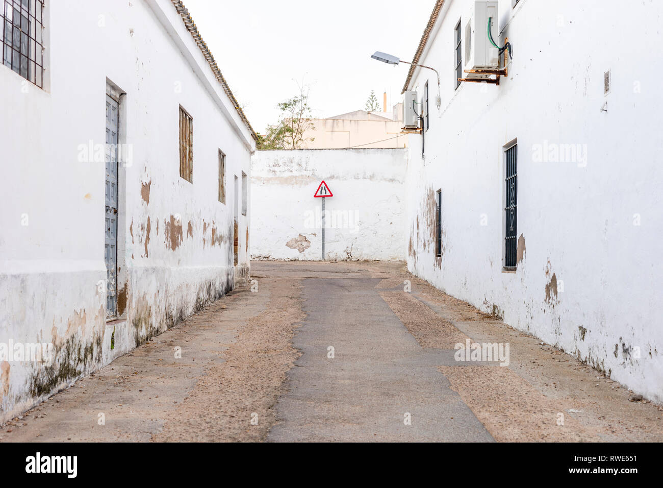 Strada si restringe accedi alla fine della strada stretta con malandata di edifici bianchi Foto Stock