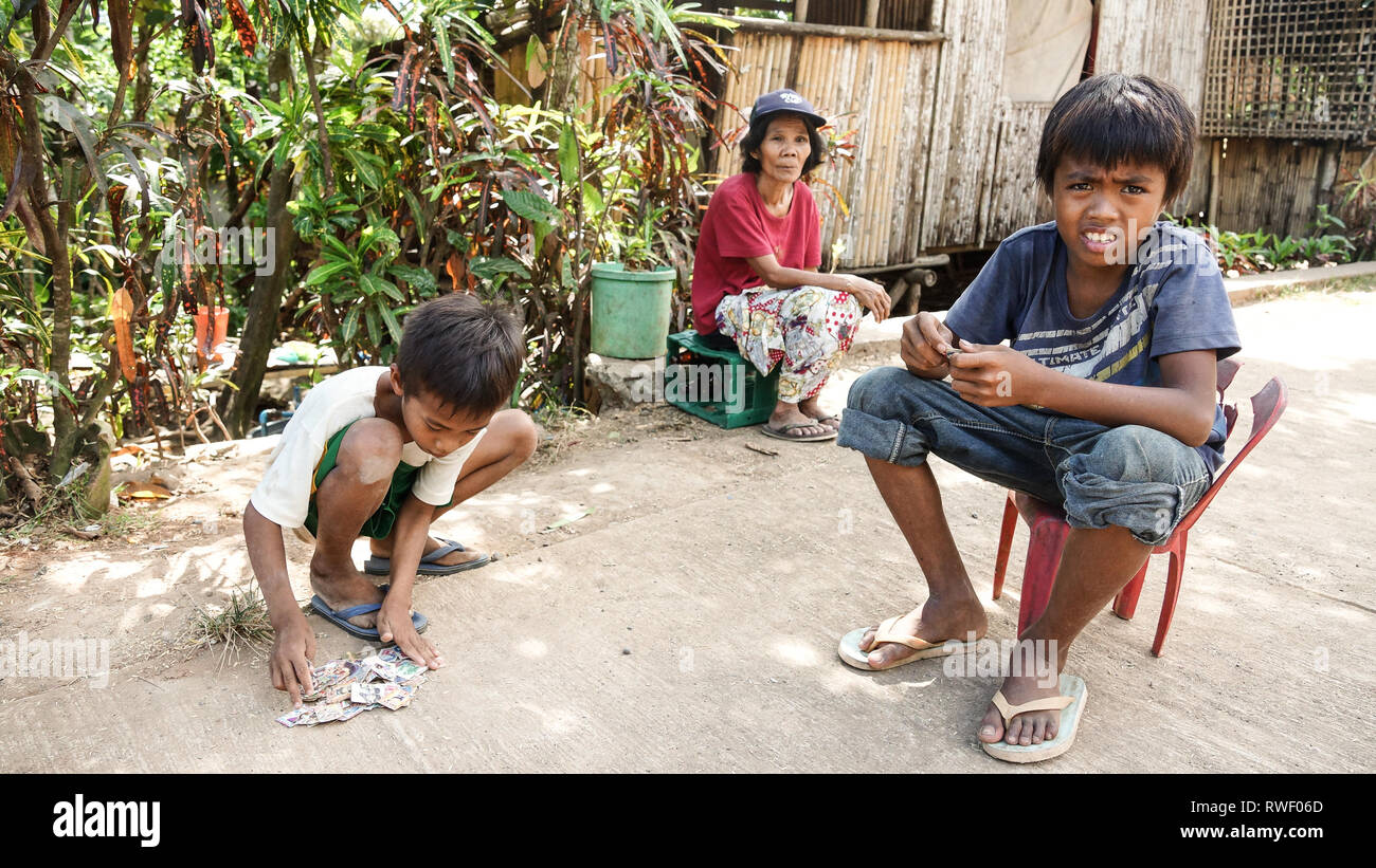 Ragazzi giocare filippino scheda di gioco nel Village Street, con la nonna, Tibiao, antichi - Filippine Foto Stock