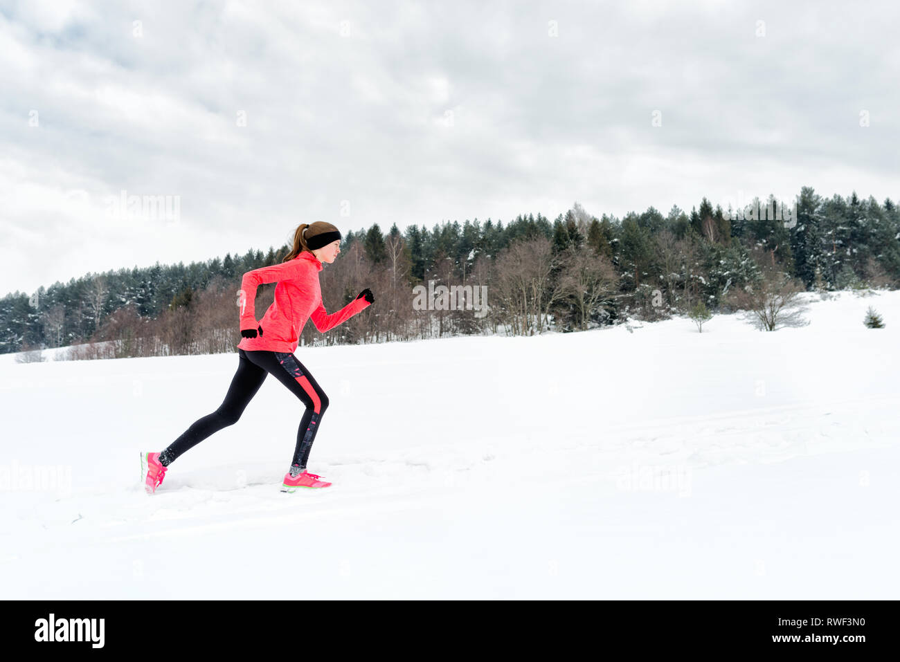 Giovane donna in esecuzione sulla neve in inverno le montagne di indossare abiti caldi guanti in caso di neve. Sport e fitness ispirazione e motivazione. Felice teen w Foto Stock