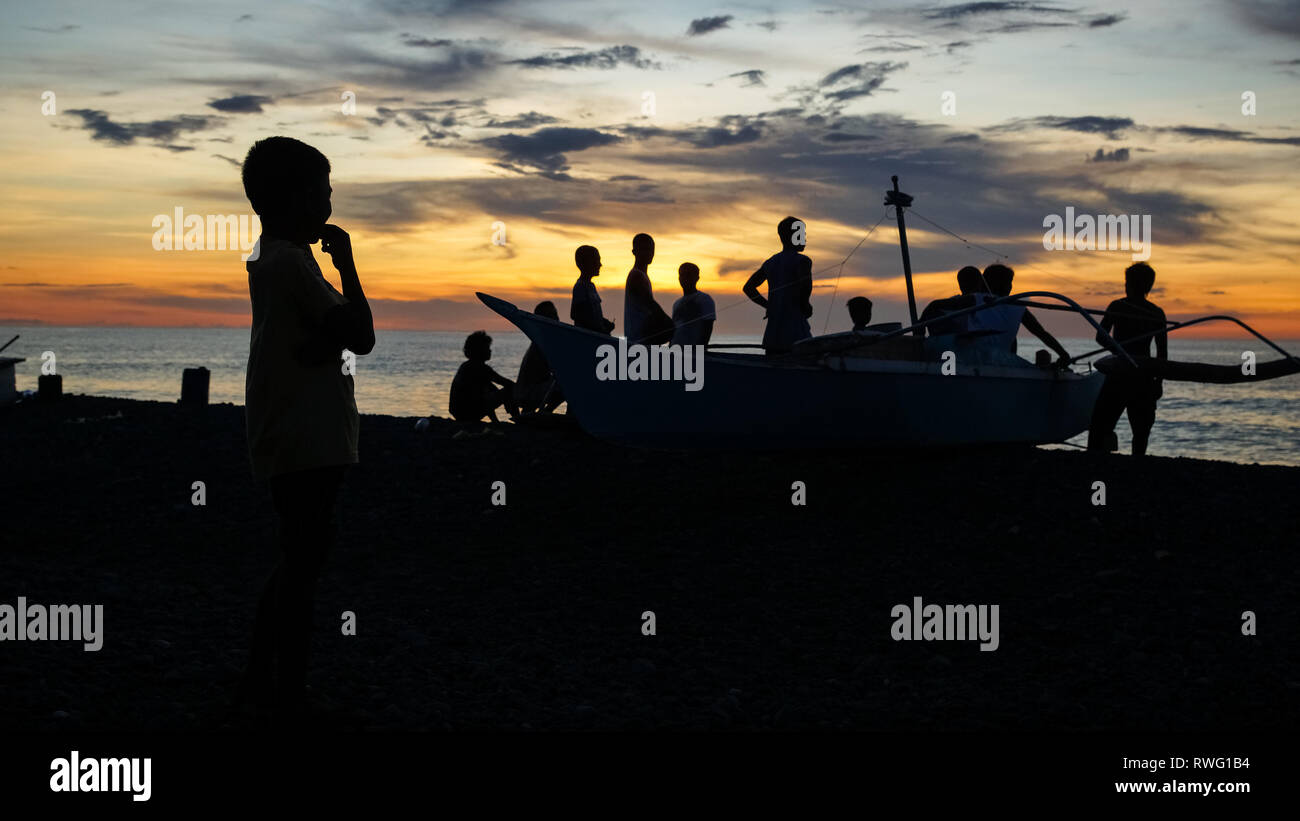 Gruppo di pescatori in piedi in barca sulla spiaggia al tramonto - Tibiao, antichi - Filippine Foto Stock