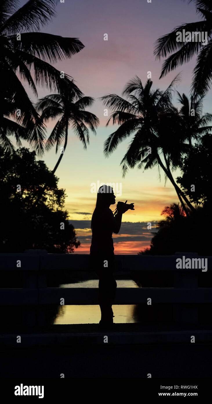 Donna Traveler tenendo isola le foto con la fotocamera DSLR - Silhouette di Boracay Island - Filippine Foto Stock