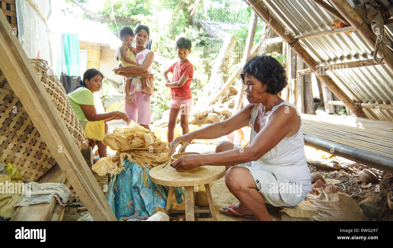 Donna filippina facendo lavori in ceramica, con la figlia e i nipoti - Tibiao, antichi - Filippine Foto Stock