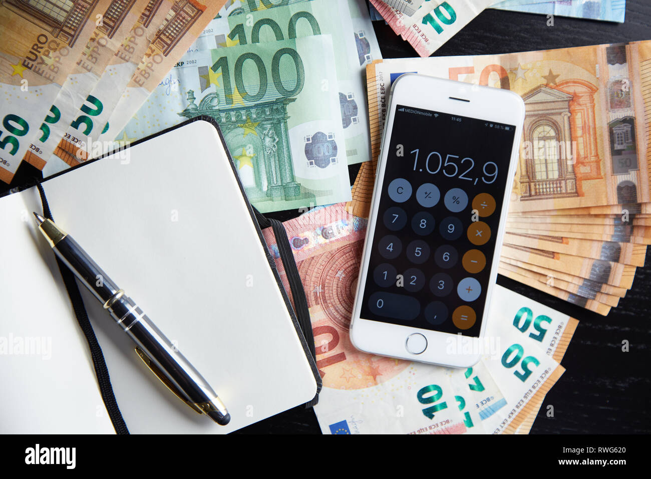 Smartphone con la Calcolatrice sul lotto di banconote in euro di denaro e aperto il notebook il concetto di Business Foto Stock