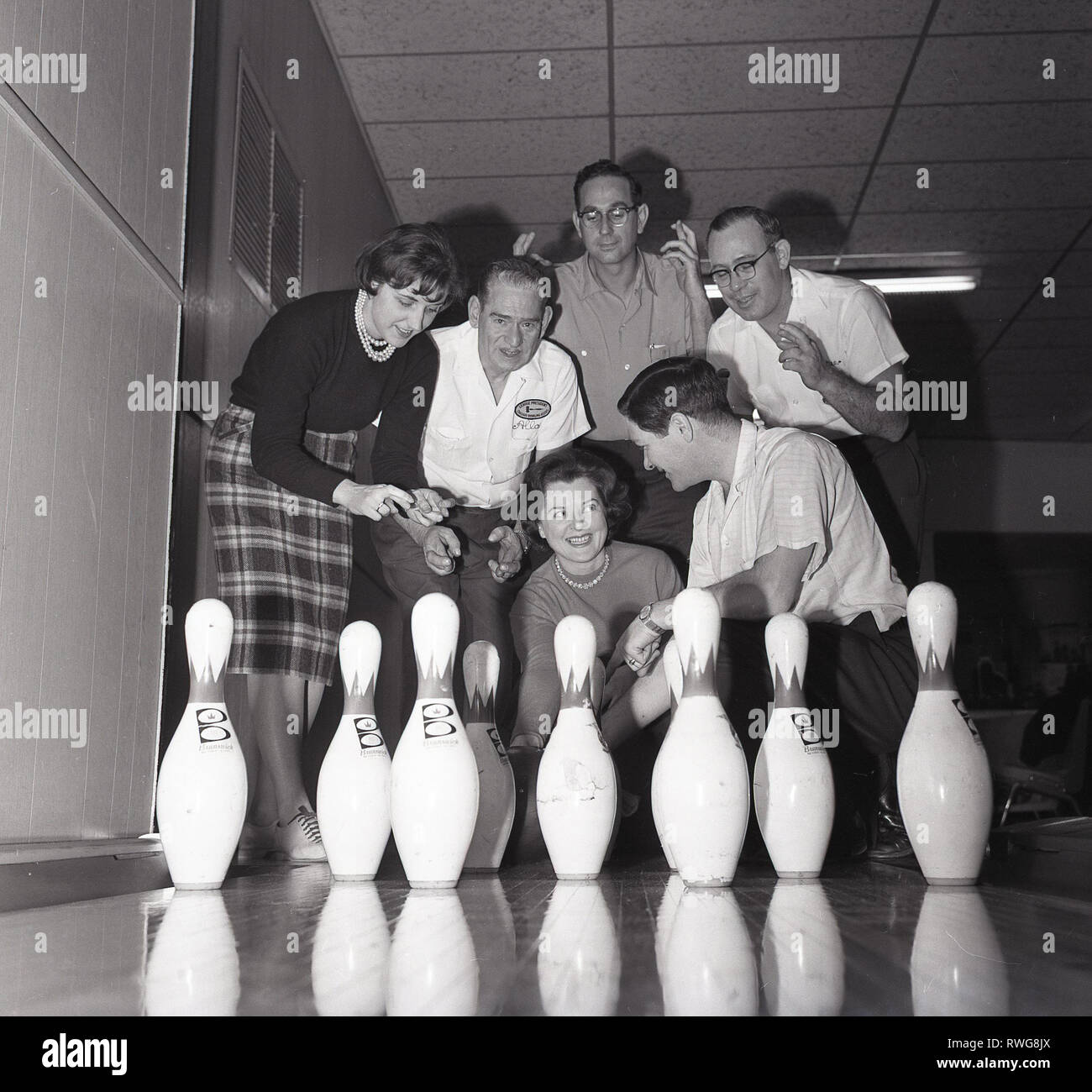 Anni sessanta, maschio e femmina giocatori di bocce incrocio le dita sperando per una casa in pieno un gioco di bowling a dieci birilli, in corrispondenza di una pista da bowling a Chicago, Stati Uniti d'America. Foto Stock
