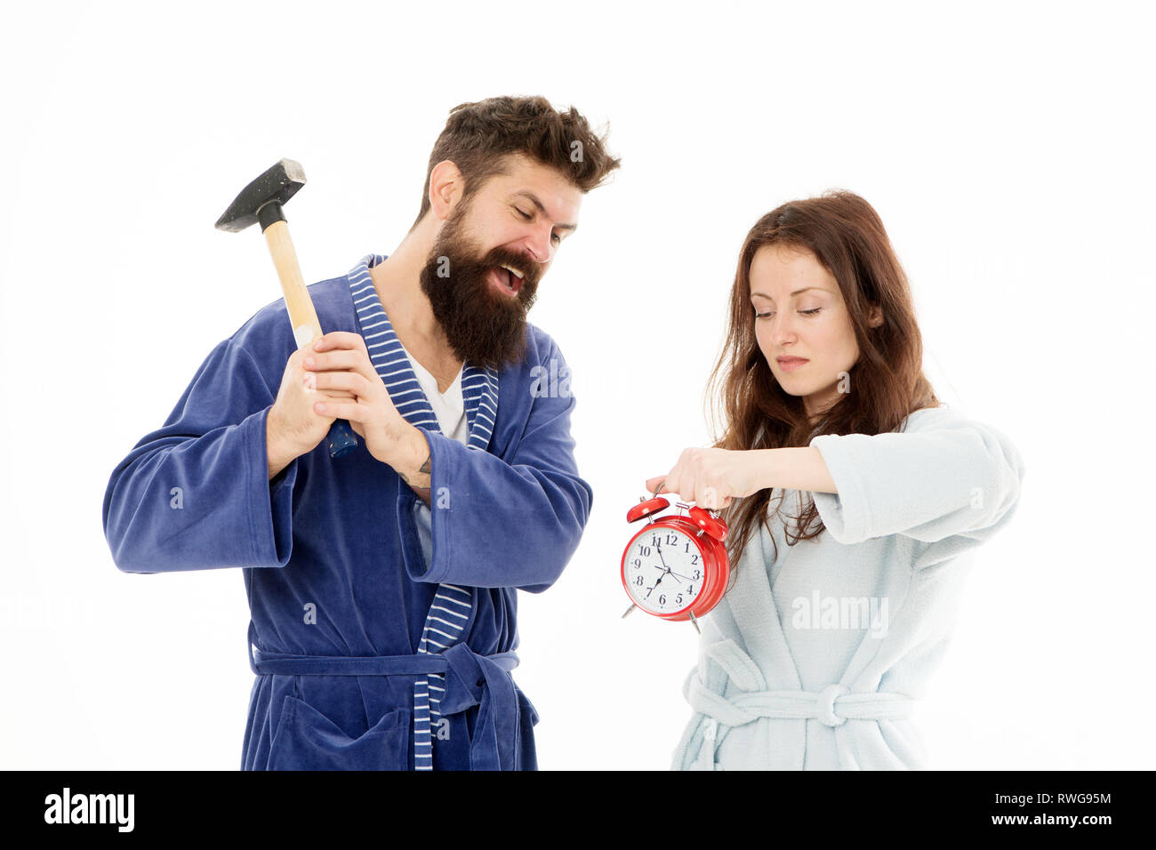 Rabbia e odio. La mattina presto l'ansia. Sbarazzarsi di fastidiosi sveglia. Coppia di accappatoi andando a distruggere la sveglia e rimanere a casa propria. Regole di rottura. Uomo con un martello battere sveglia. Odioso suono. Foto Stock