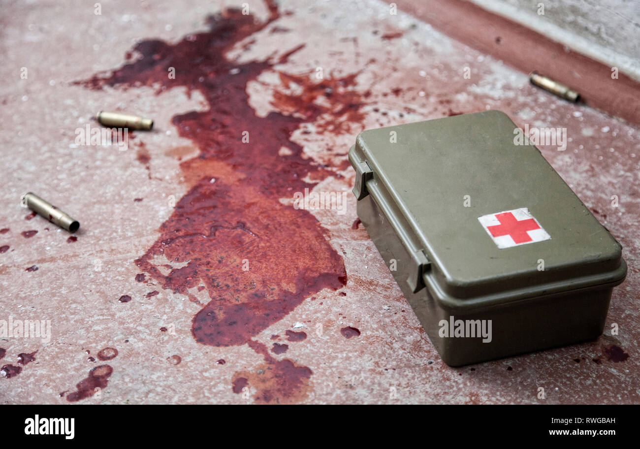 Military first aid kit sul pavimento con vuoto involucri punto e fresche macchie di sangue umano. Foto Stock