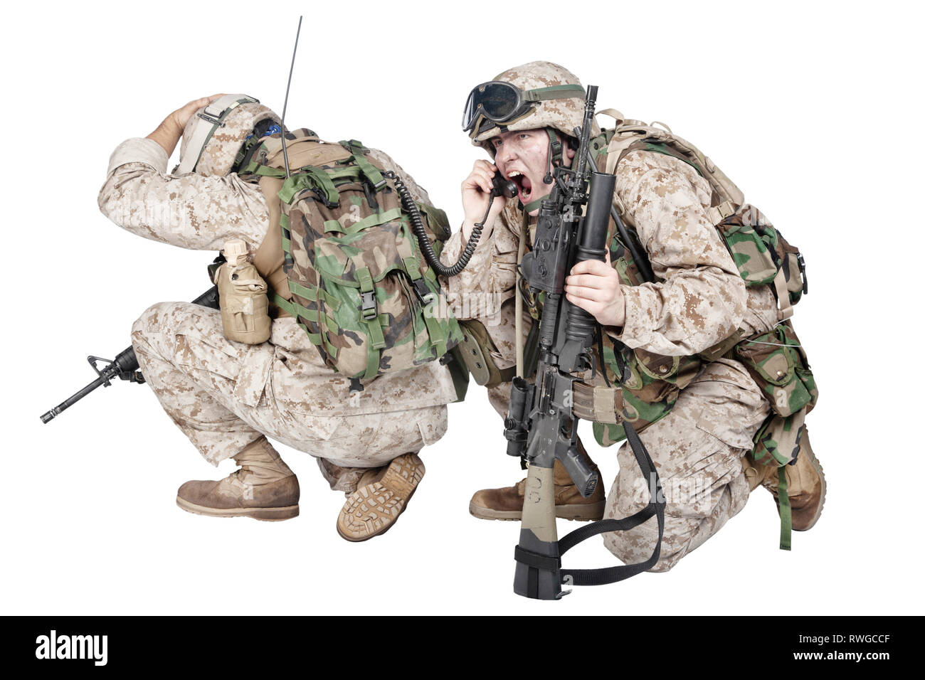 Soldati accovacciato a terra a parlare alla radio mentre sotto il fuoco nemico. Foto Stock