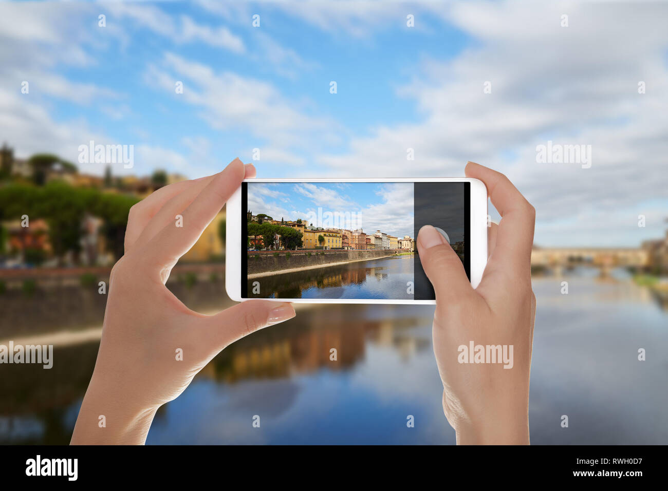 Un uomo è fare una foto di banchina del fiume Arno e Ponte Vecchio a Firenze, Italia su un telefono cellulare Foto Stock