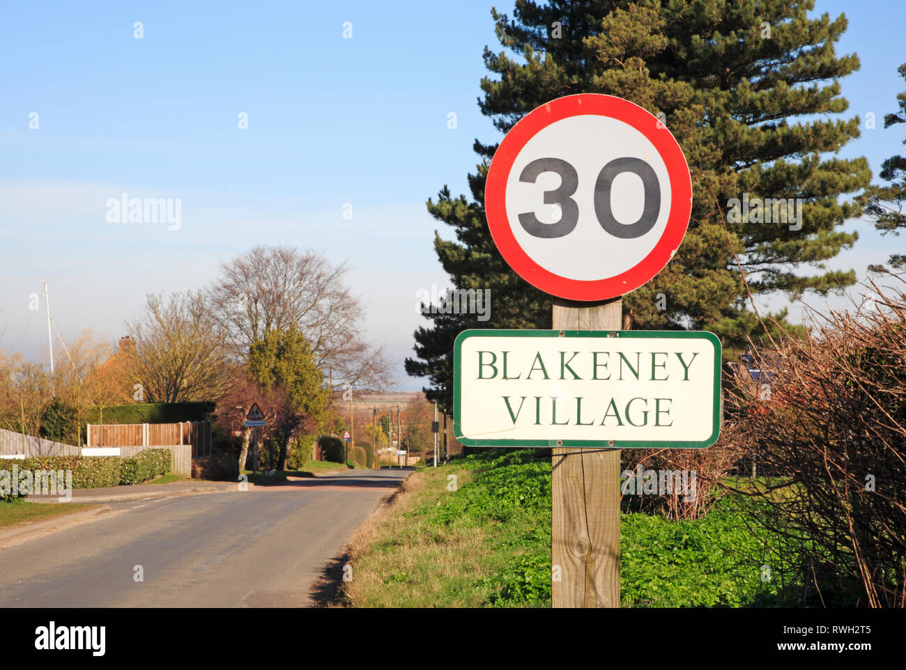 A 30 mph segno e nome del villaggio del Langham Road entrando nel North Norfolk villaggio di Blakeney, Norfolk, Inghilterra, Regno Unito, Europa. Foto Stock