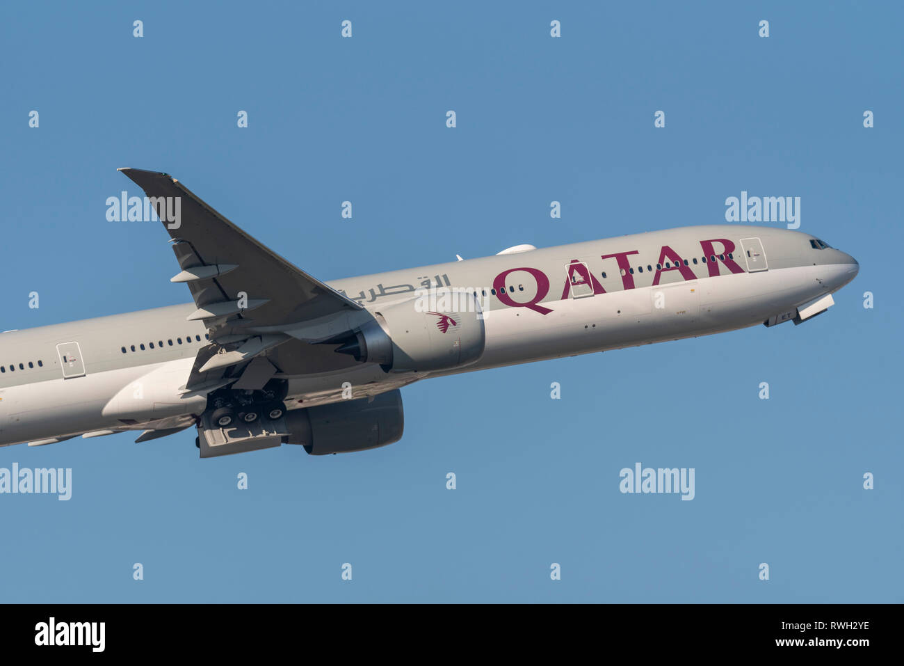 Qatar Airways Boeing 777 aereo di linea A7-BET decolla dall'aeroporto Heathrow di Londra, Regno Unito, in cielo blu Foto Stock
