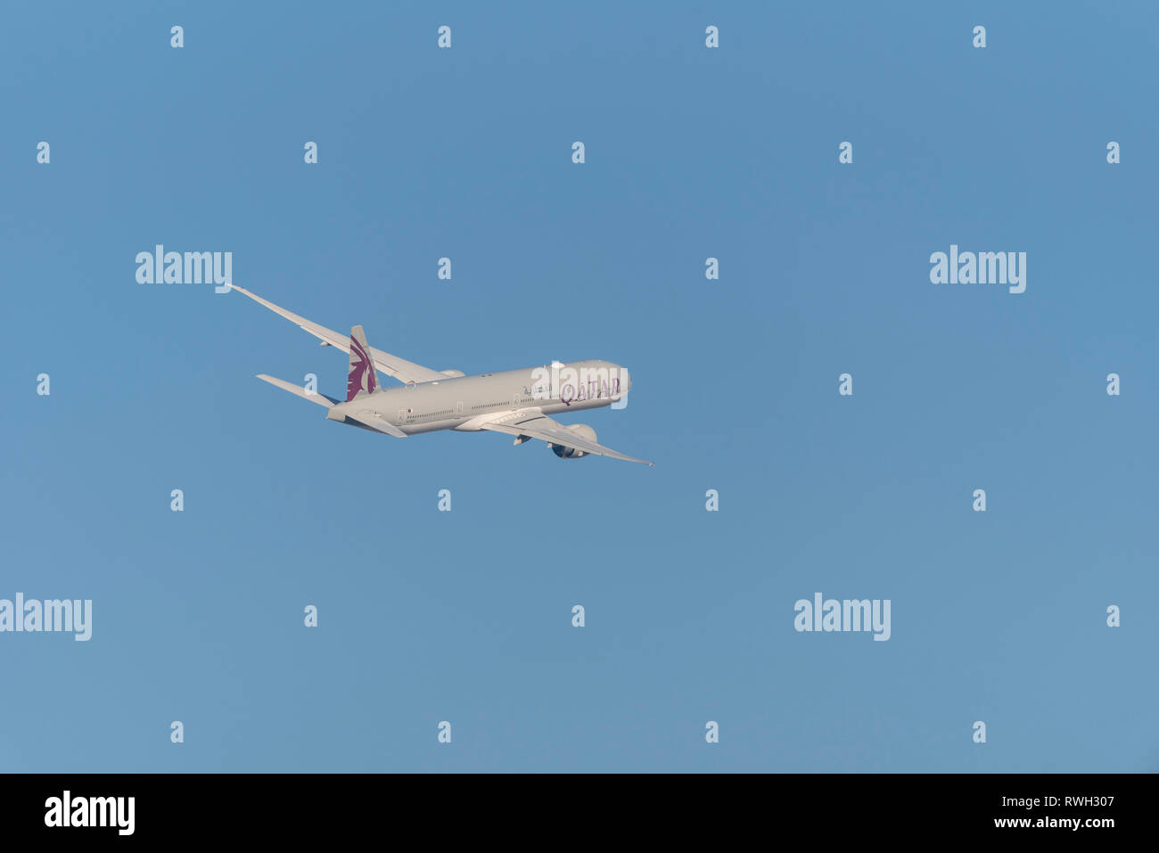 Qatar Airways Boeing 777 aereo di linea A7-BET decolla dall'aeroporto Heathrow di Londra, Regno Unito, in cielo blu Foto Stock