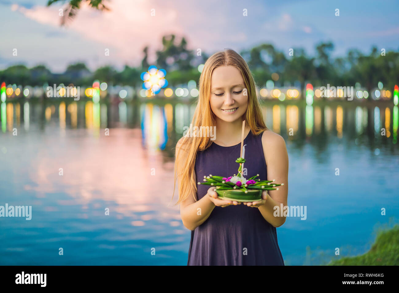 Giovane donna celebra Loy Krathong, corre sull'acqua. Loy Krathong festival, la gente compra i fiori e candela alla luce e galleggiare su acqua per celebrare Foto Stock