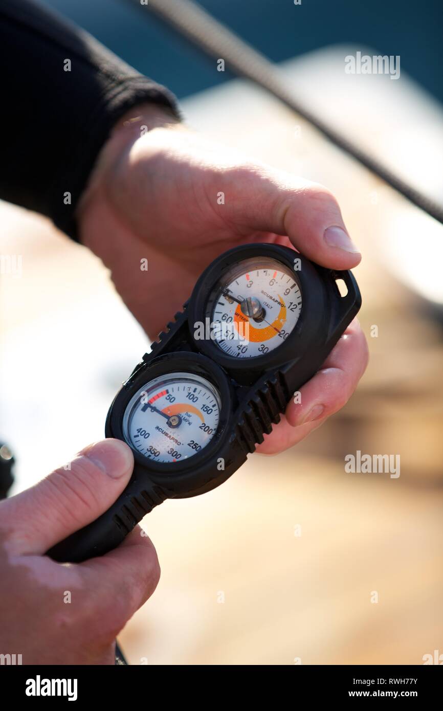 Extreme Close up subacqueo mani del controllo del misuratore di ossigeno regolatore sulla barca Foto Stock