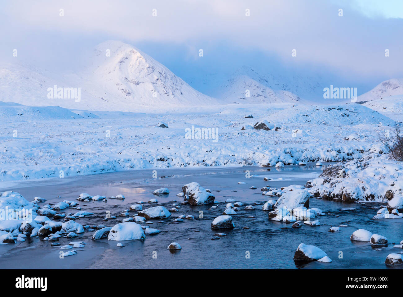 Il freddo inverno mattina con il sorgere del sole sulle montagne di illuminazione con congelati loch e neve a Loch Ba, Rannoch Moor, Argyll and Bute, Scozia in gennaio Foto Stock