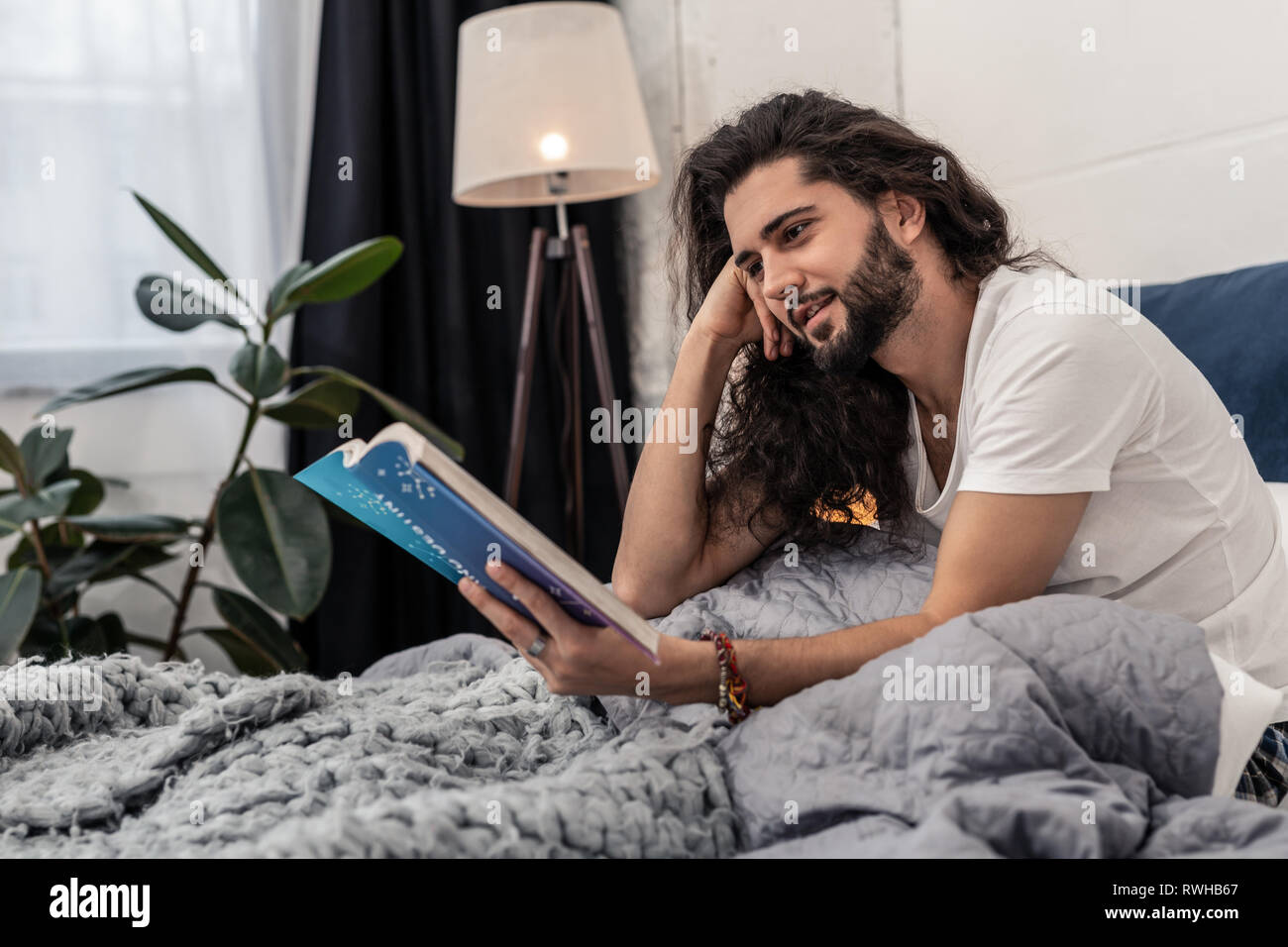 Positivo bella giovane uomo concentrandosi sulla lettura Foto Stock
