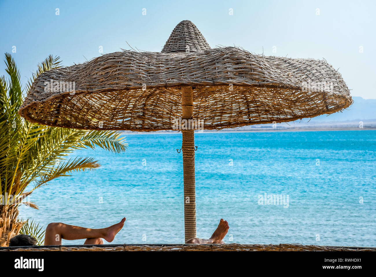 Ombrellone a maglia con bastoni di legno che forniscono ombra naturale  sulla spiaggia in una giornata di sole Foto stock - Alamy