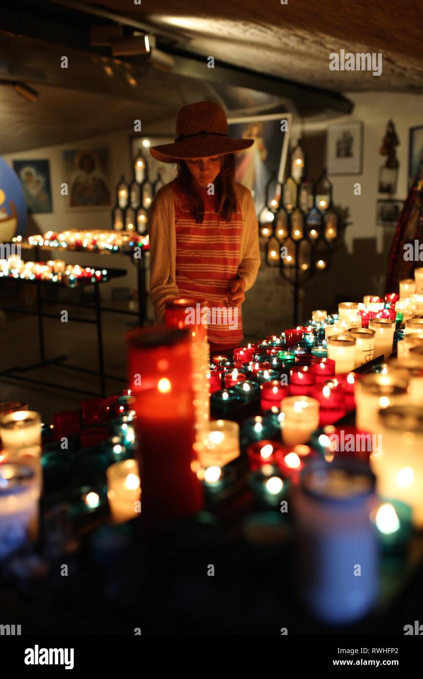 Bella ragazza giovane accende una candela nella cripta della chiesa di Saintes-Maries-de-la-Mer, la Camargue. Foto Stock