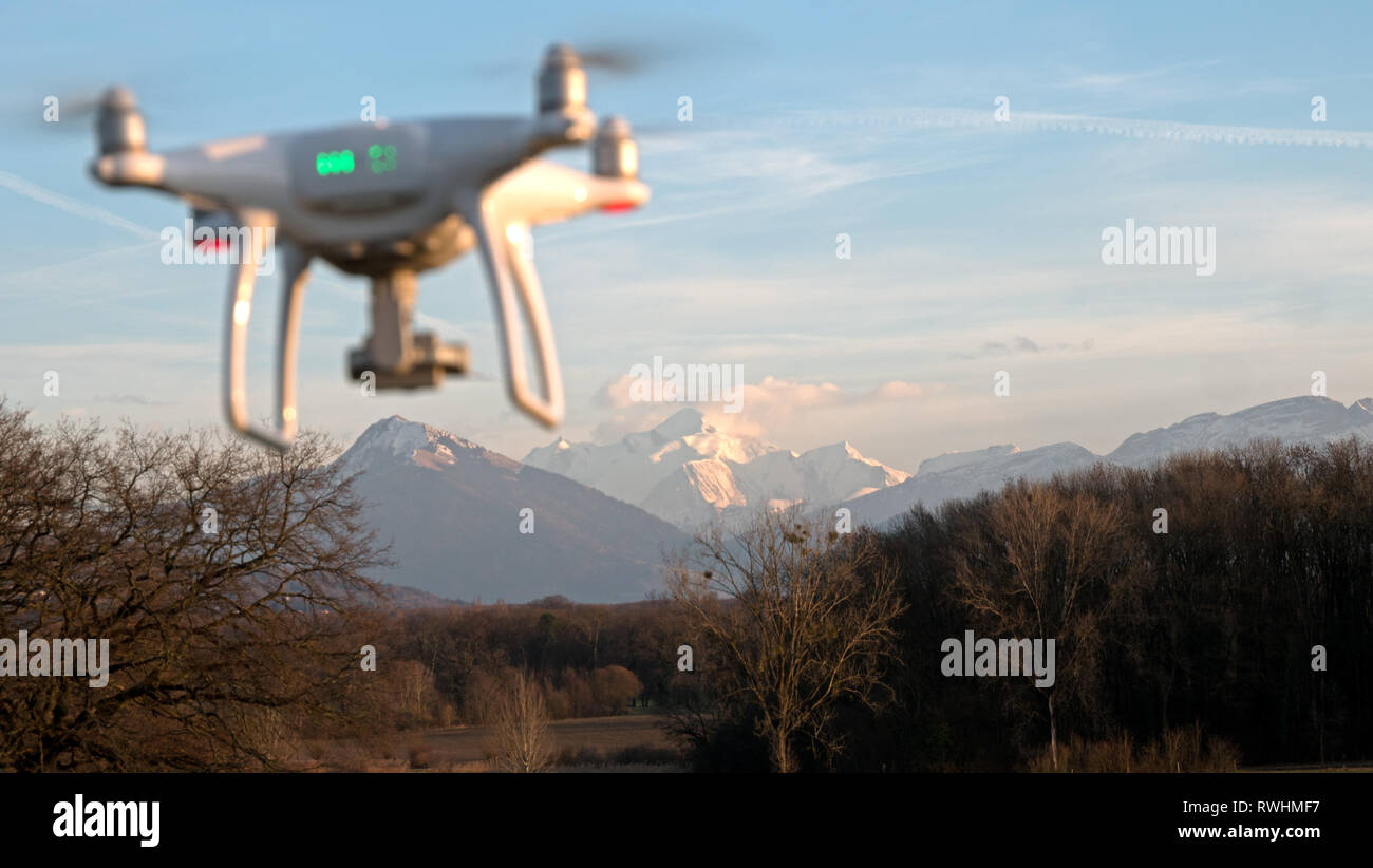 Un drone si libra in volo nella parte anteriore di un tramonto sullo sfondo. Il drone è fermo in bilico sopra la terra come i tramonti in distanza. Foto Stock