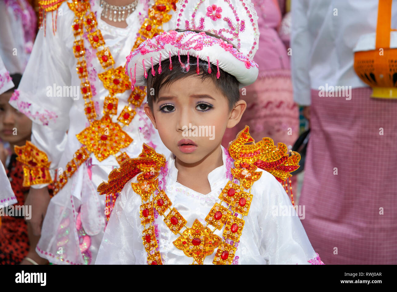 Un giovane ragazzo birmano vestito in costume buddista e la faccia fatta con il trucco assiste la sua venuta di età cerimonia in Myanmar Mandalay Foto Stock