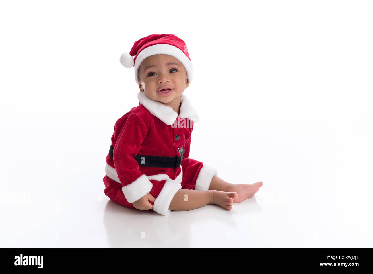 Sorridente sei mesi bambina indossa un Santa Claus costume. Fotografato in studio su un bianco, sfondo senza giunture. Foto Stock