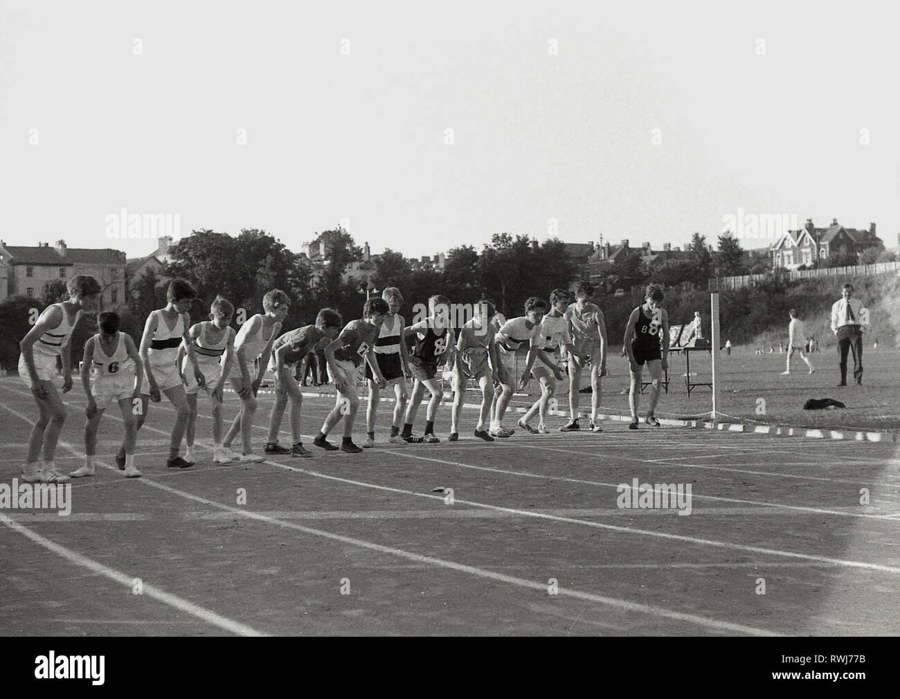 Anni sessanta, atletica amatoriale, un gruppo di ragazzi linea fino all'inizio di una gara di corsa su pista, indossando un assortimento di differenti calzature, principalmente plimsolls, Inghilterra, Regno Unito. Foto Stock