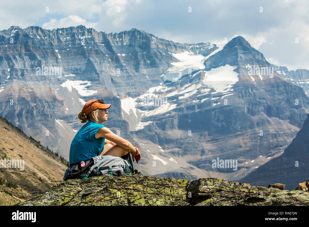 Escursionista femmina seduto su una zona rocciosa che si affaccia mountain vista in background; British Columbia, Canada Foto Stock