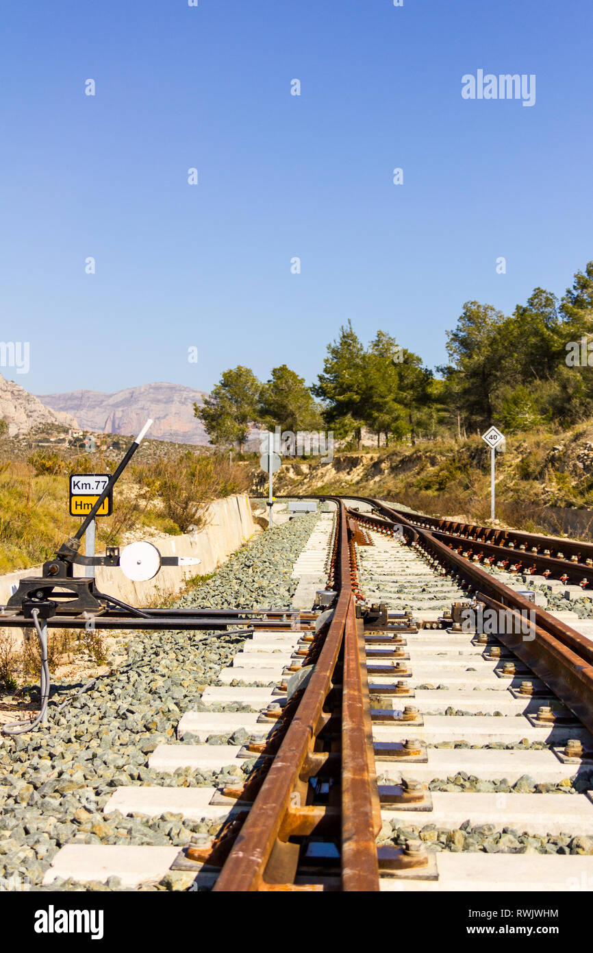 Un deviatoio ferroviario via con cartelli stradali, montagne e gli alberi in background Foto Stock