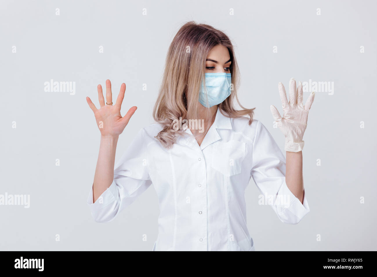 Ritratto di donna medico con una maschera facciale medico mostra le mani. una mano e l'altra senza Foto Stock