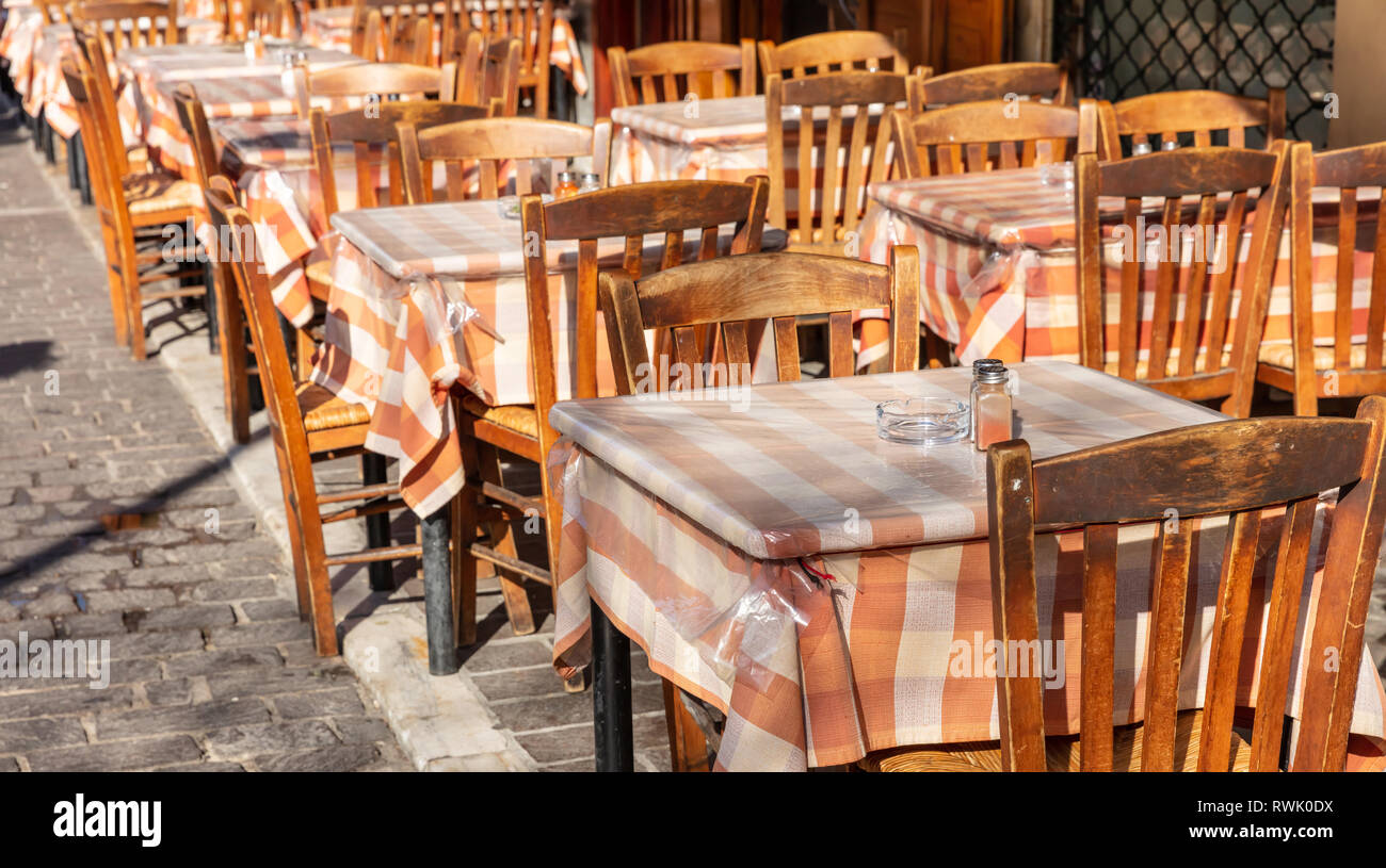 Il greco tipica taverna all'aperto, svuotare i tavoli e le sedie, giornata soleggiata, centro città Foto Stock
